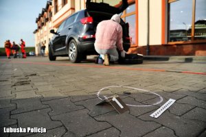 zabezpieczony ślad w tle technik wykonujący oględzin pojazdu