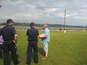 policjanci i pracownik ośrodka przy jeziorze