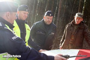 policjanci i strażnik leśny oglądają mapę