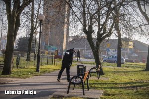 policjant dokonujący sprawdzenia wnętrza kosza w parku