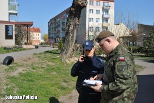 żołnierz i policjantka na tle osiedla. Policjanta rozmawia przez telefon