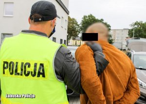 policjant prowadzi zatrzymanego mężczyznę