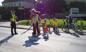 dzieci przechodzą przez przejście dla pieszych razem z maskotką policyjną