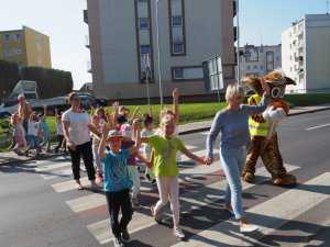 dzieci z podniesionymi rękami przechodzą przez przejście dla pieszych