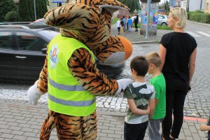 policyjny tygrysek lupo stoi wraz z dzieckiem przy przejściu dla pieszych
