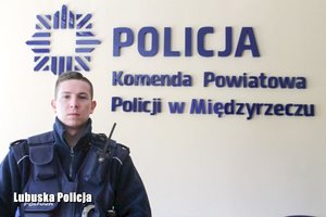zdjęcie przedstawia sierżanta sztabowego Michała Ostaszewskiego w mundurze na tle napisu Komenda Powiatowa Policji w Międzyrzeczu