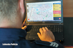 policjant siedzący tyłem przed laptopem z włączoną na ekranie z aplikacją Krajowa Mapa Zagrożeń Bezpieczeństwa