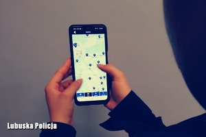 policjantka trzymająca w dłoni telefon z włączoną aplikacją Moja Komenda