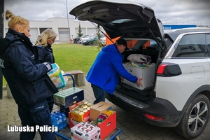 funkcjonariusze oraz pracownik cywilny w trakcie pakowania darów dla obywateli Ukrainy do samochodu