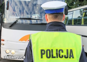 policjant stojący tyłem w tle przednia część autokaru
