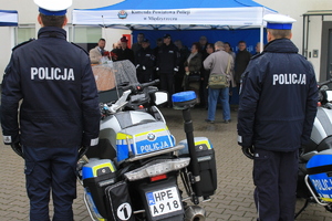 Policjanci w trakcie uroczystości przekazania i święcenia radiowozów. Zdjęcie ukazuje policjantów stojących przy motocyklach