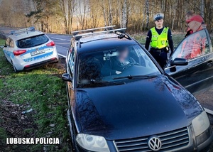 pojazd osobowy z otwartymi drzwiami kierowcy, obok nich stojący policjant oraz ratownicy medyczni