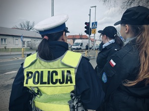 policjanta oraz uczniowie w trakcie nadzoru przejścia dla pieszych