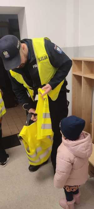 policjant nakłada kamizelkę odblaskową dziecku