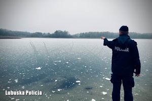 policjant wskazujący dłonią na tafle zamarzniętego jeziora