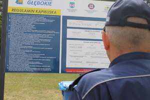 zdjęcie zrobione od tyłu. Ramie policjanta w tle regulamin kąpieliska