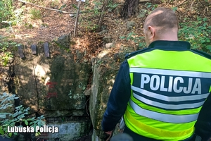 policjant stojący tyłem do wejścia podziemnego do bunkru