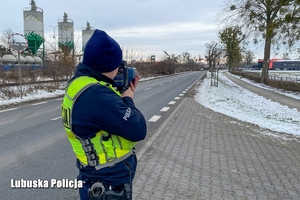 policjant w trakcie dokonywania pomiaru prędkości na drodze