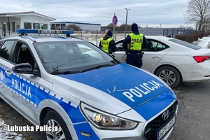 policyjny radiowóz w tle policjanci przy kontrolowanym pojeździe