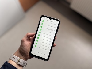 Na zdjęciu widzimy telefon komórkowy trzymany w ręku. Na ekranie telefonu komórkowego wyświetlone są zagrożenia, które można nanieść na Krajową Mapę Zagrożeń Bezpieczeństwa.