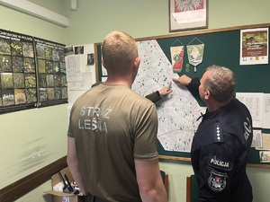 na zdjęciu widzimy przedstawicieli policji, Pszczewskiego Parku Krajobrazowego oraz Straży Leśnej, którzy omawiają zapewnienie bezpieczeństwa w sezonie letnim spoglądając na mapę regionu
