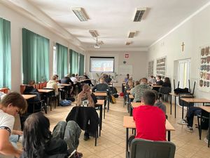 uczniowie siedzą przy ławkach i słuchają policjantki