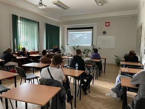 uczniowie siedzą przy ławkach i słuchają policjantki
