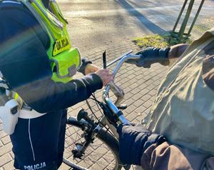 na zdjęciu policjantka oraz kierujący rowerem, któremu przyczepiany jest odblask